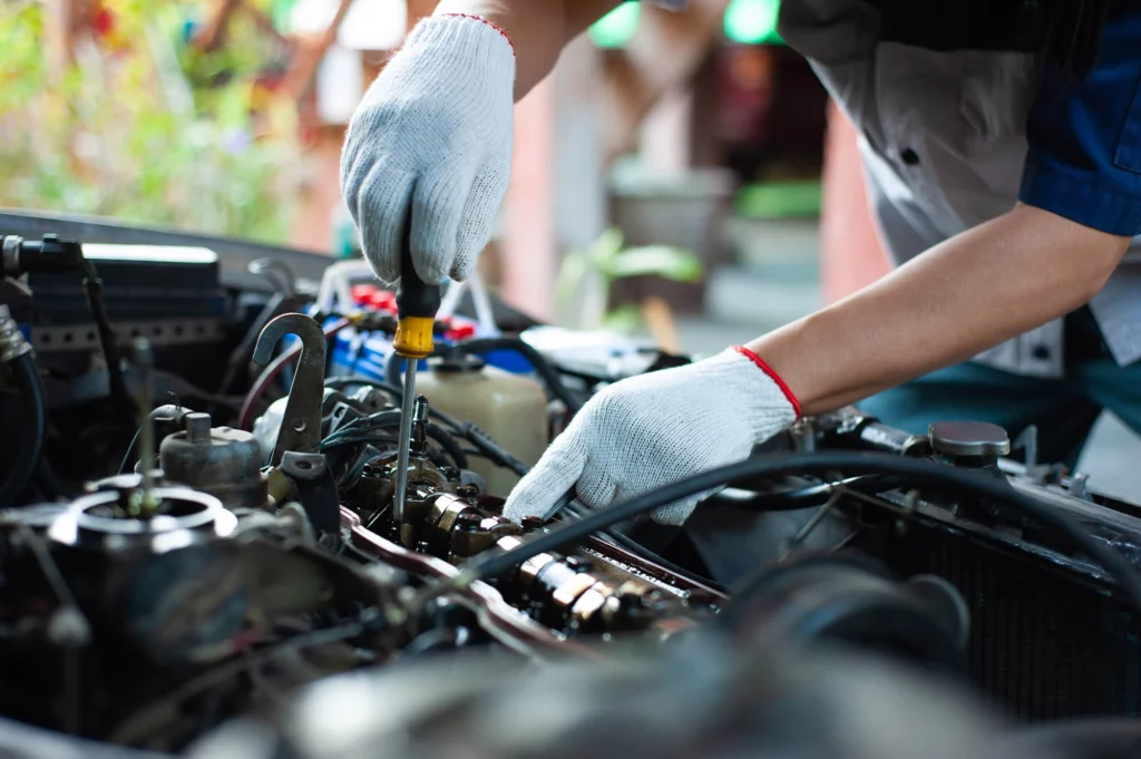 A mechanic is repairing a car about the engine's valve system.